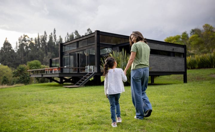 Woman and a child outside a modern house surrounded by lawns